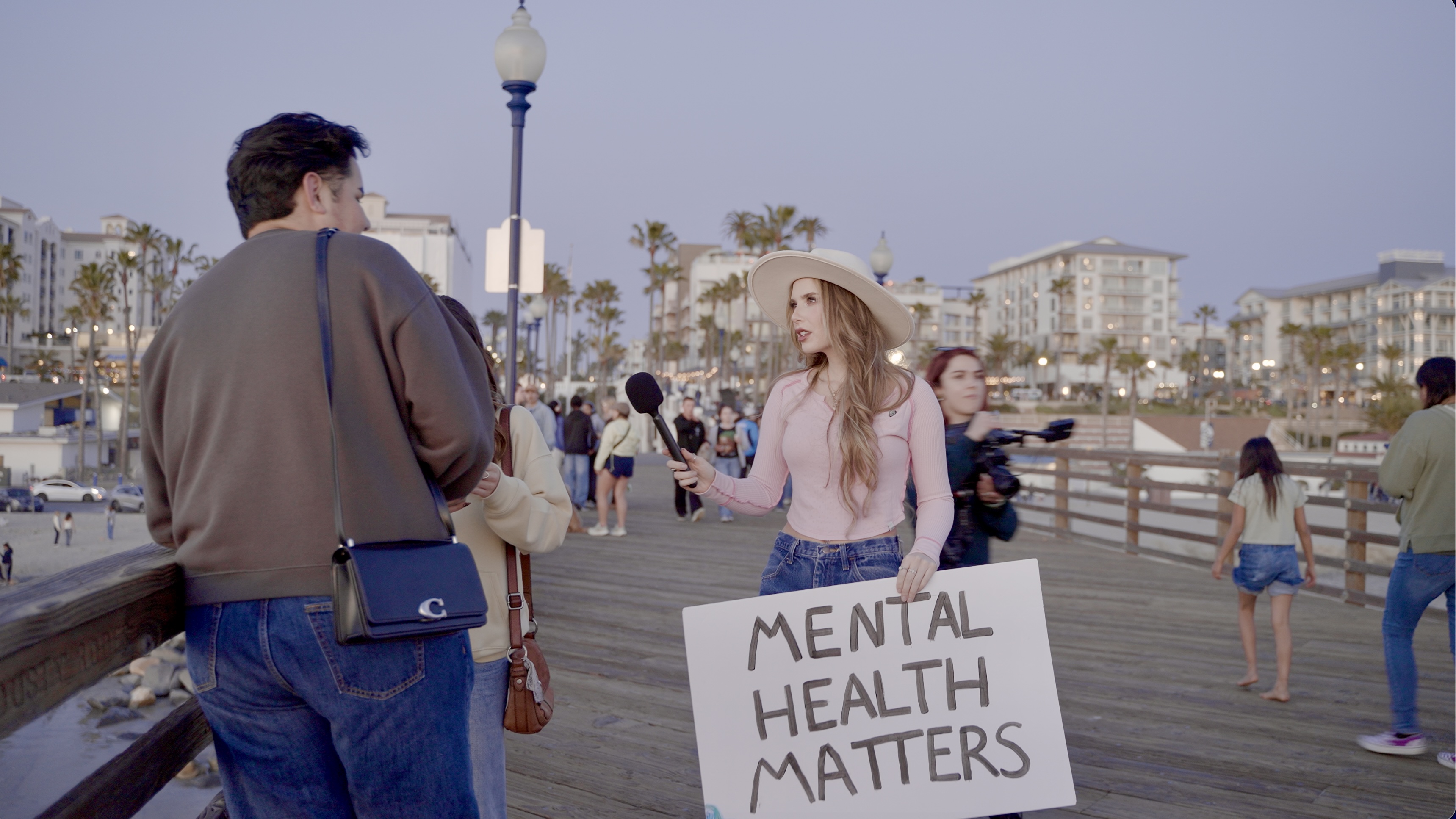 Aly Vredenburgh interviewing a young person about mental health on a California pier